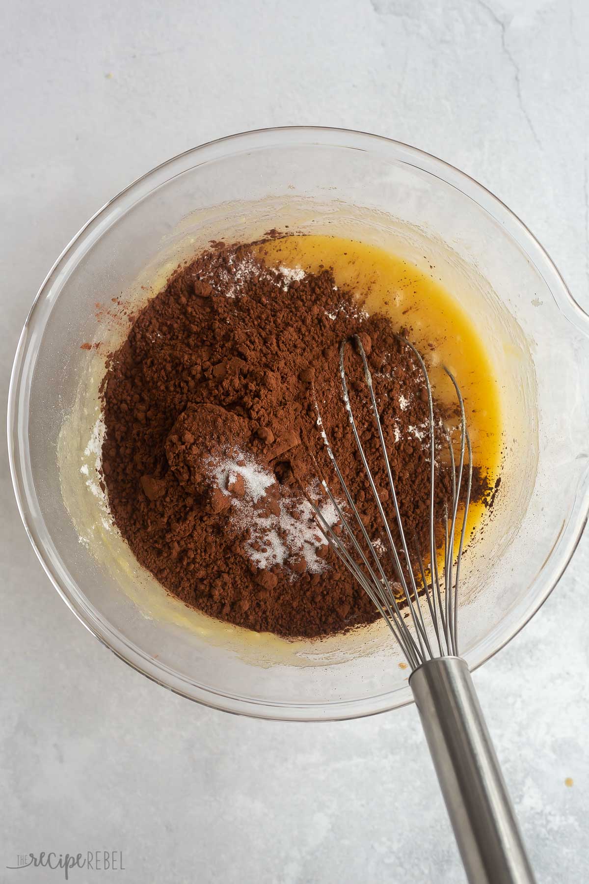 making brownie batter in a glass bowl with a whisk.