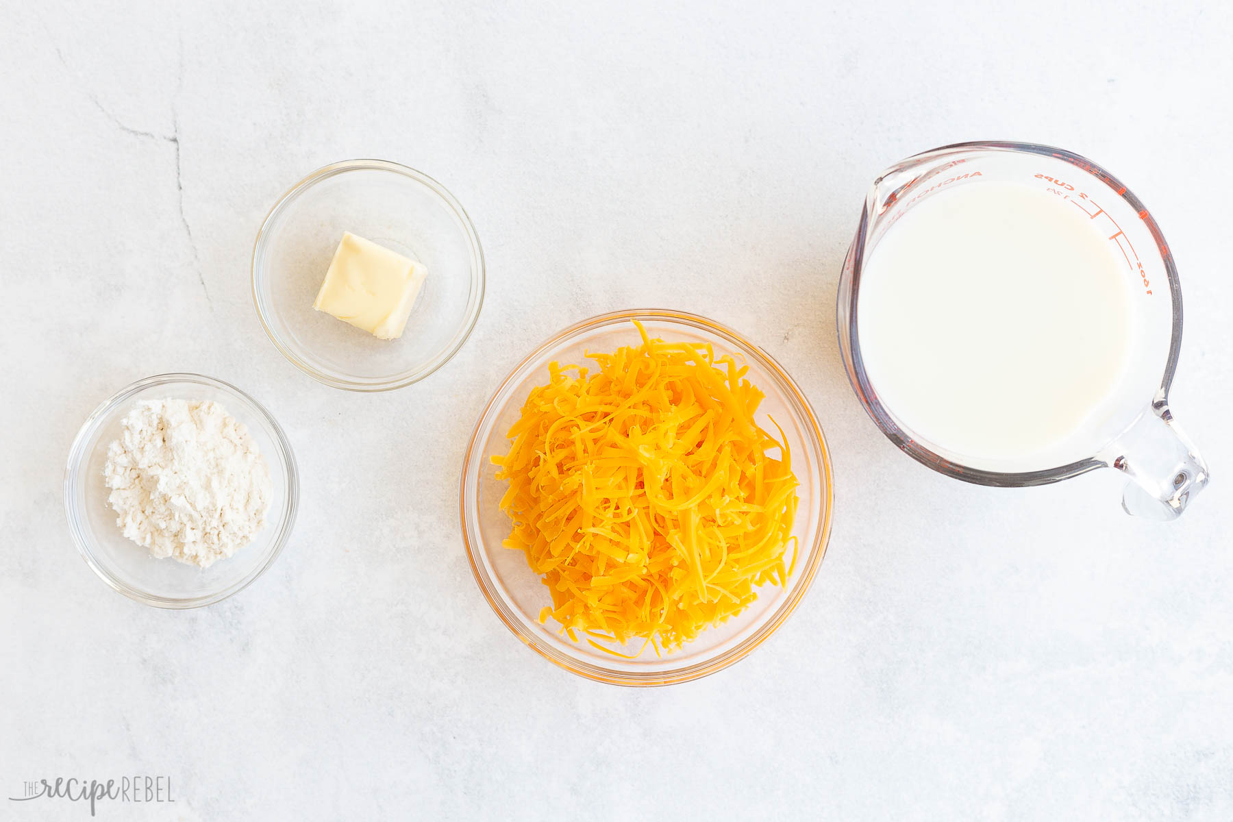 ingredients needed to make cheddar sauce on white background