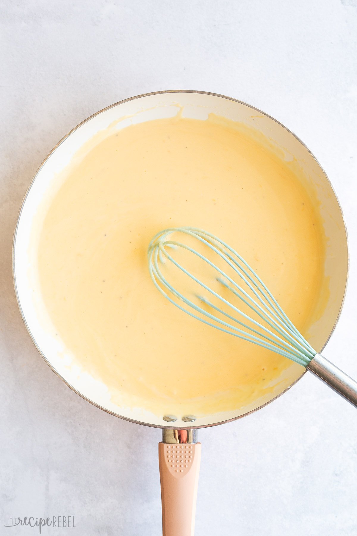 finished cheese sauce in white pan with whisk
