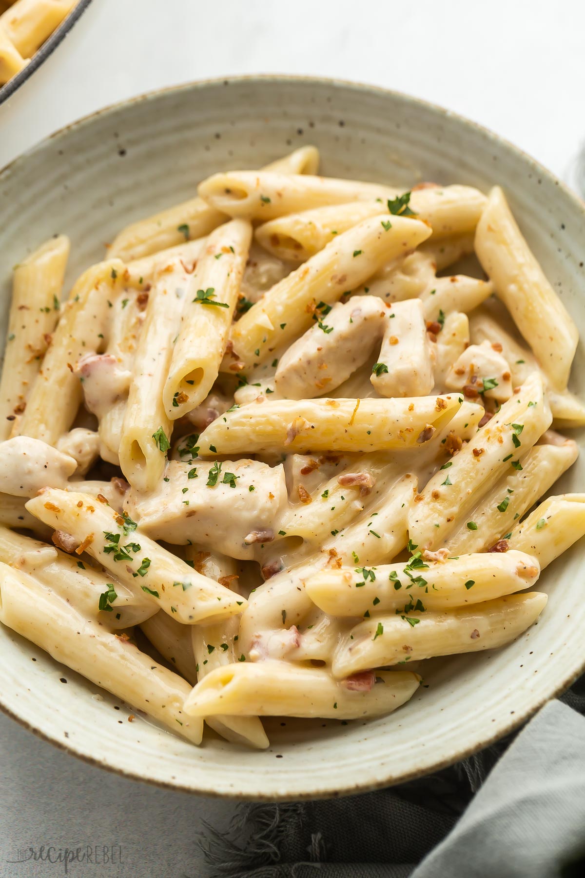 close up image of chicken bacon ranch pasta with fresh parsley and bacon