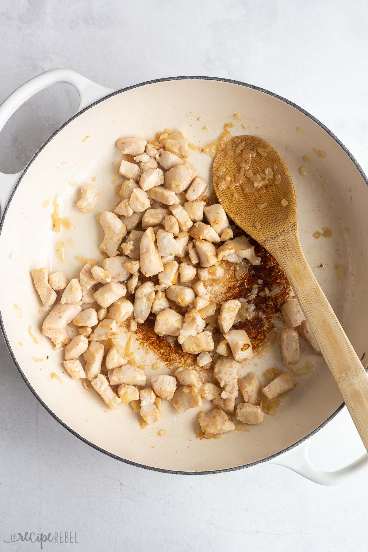 chicken pieces cooked in bacon fat in white skillet