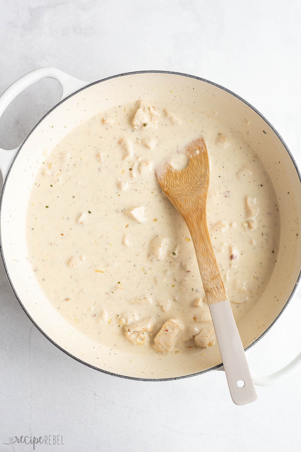 creamy sauce complete in white skillet with wooden spoon
