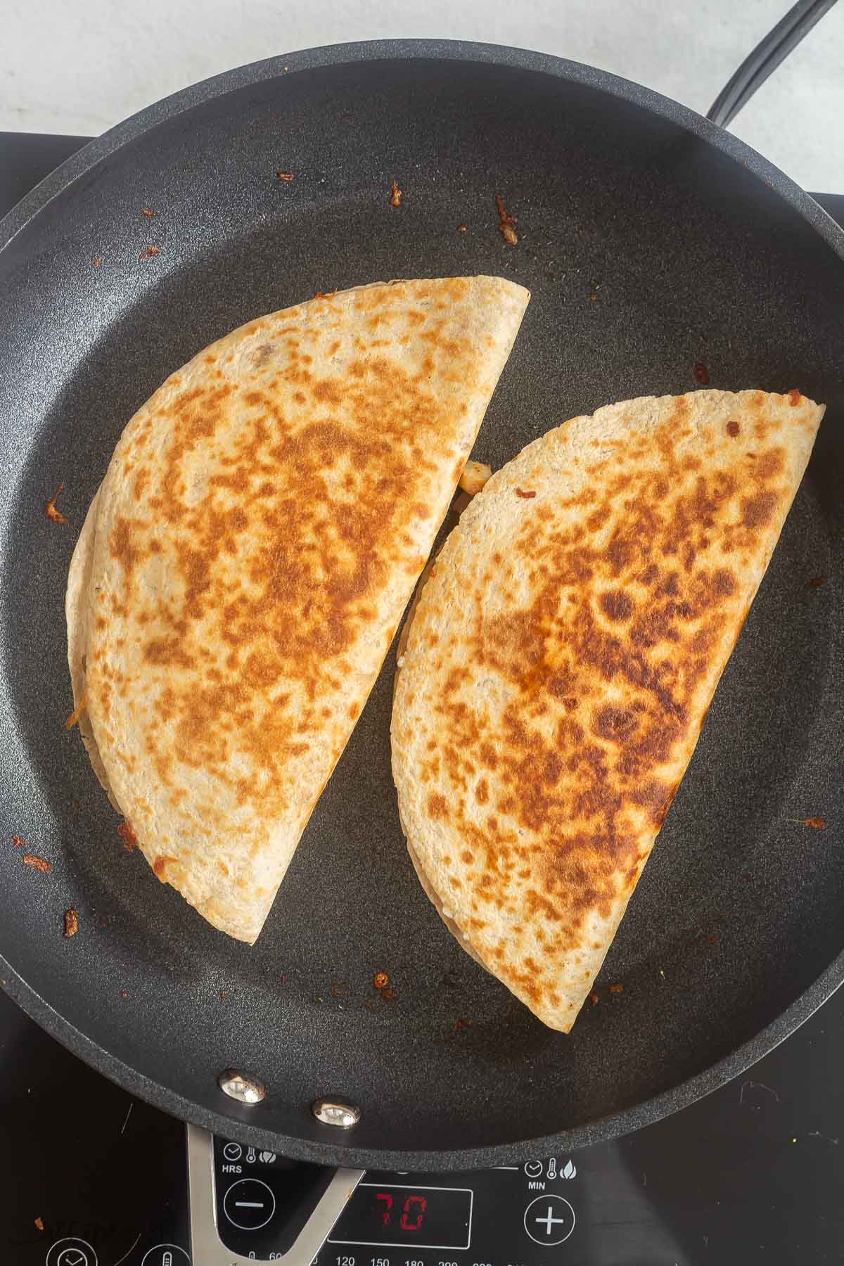 finished chicken quesadillas in a black skillet.