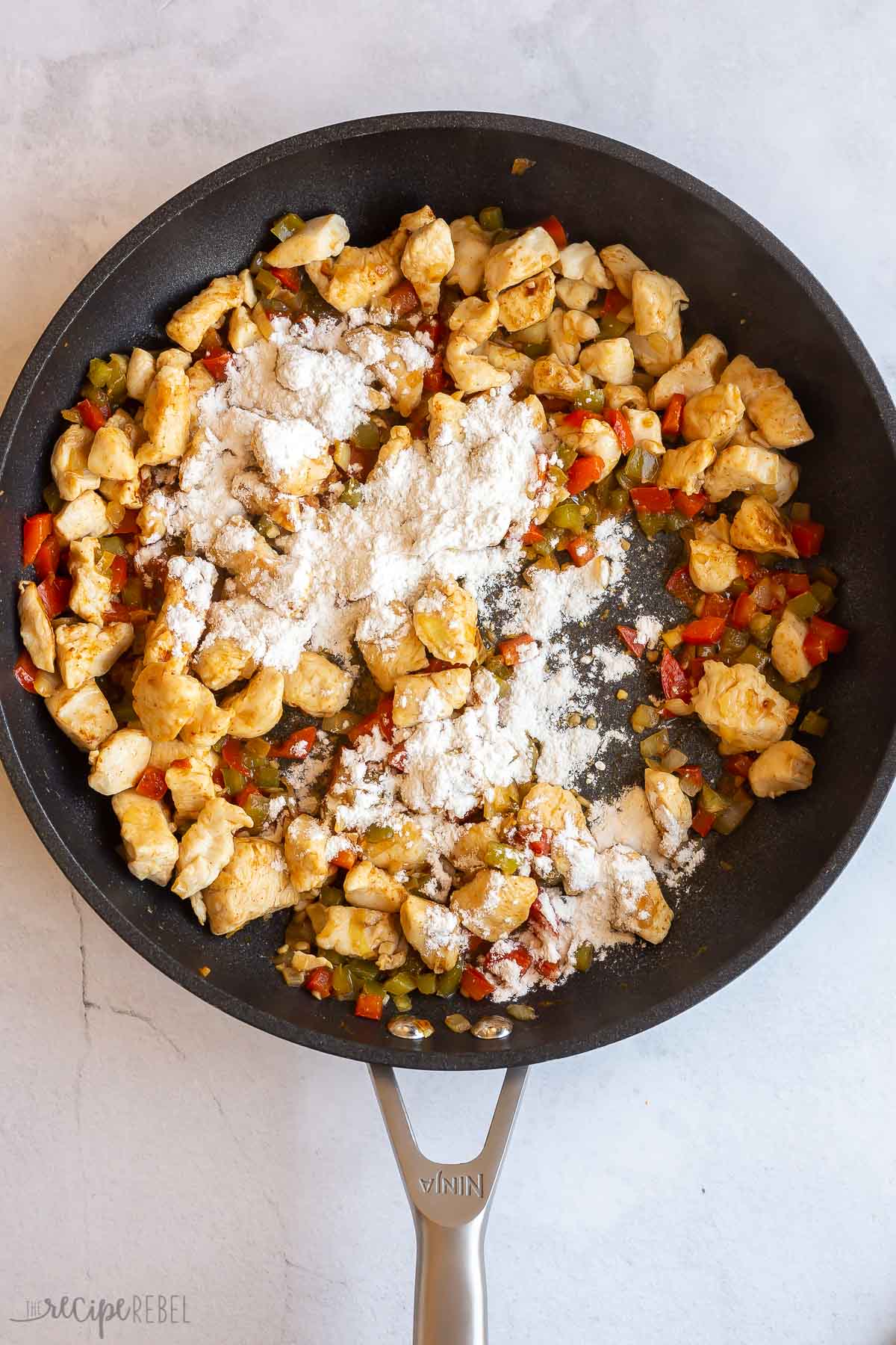 flour added to chicken and peppers in skillet.