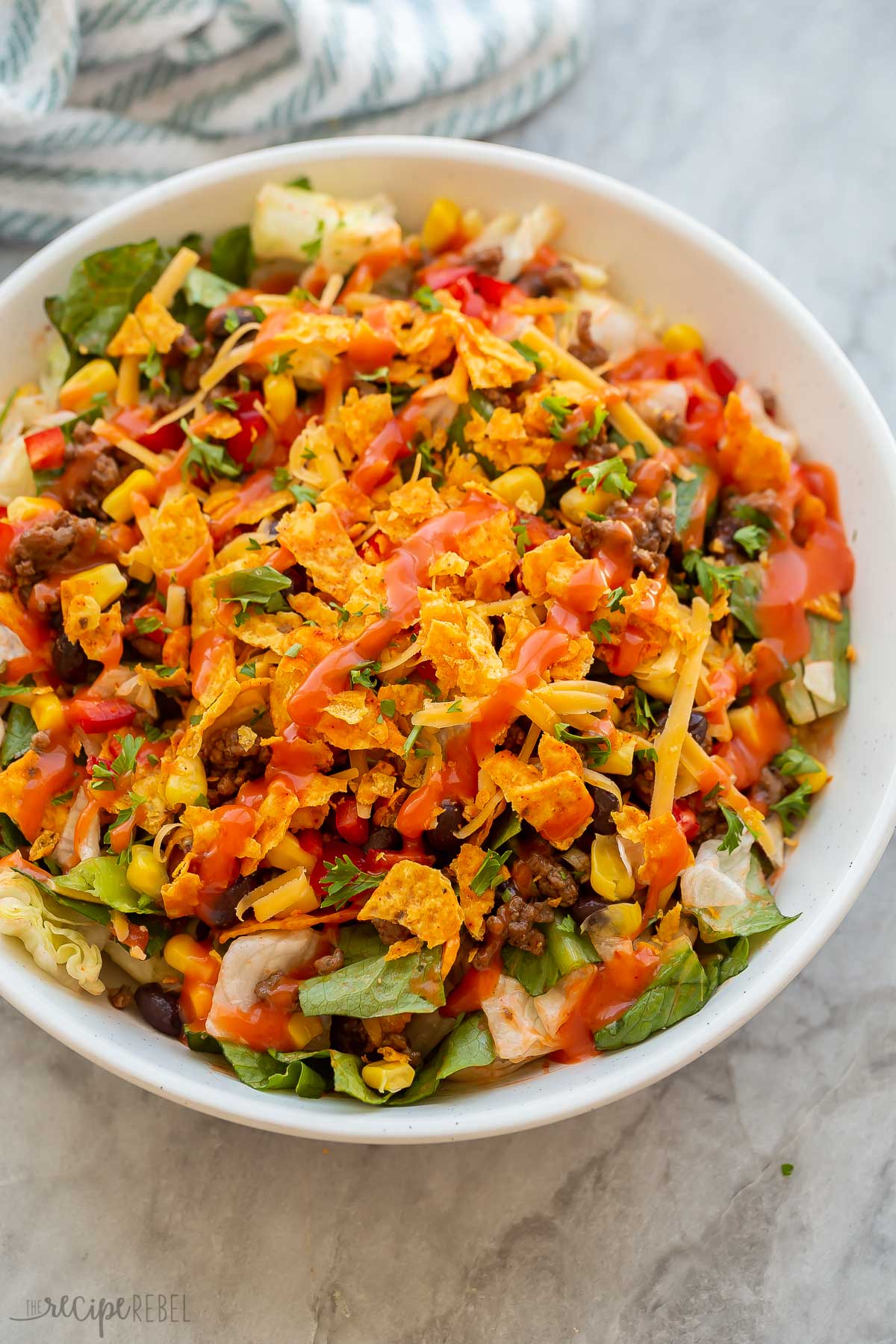 taco salad with doritos and a drizzle of catalina dressing in white bowl