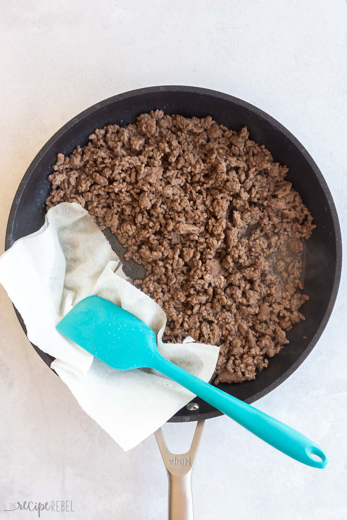 cooked ground beef in black skillet with paper towel to mop up excess grease
