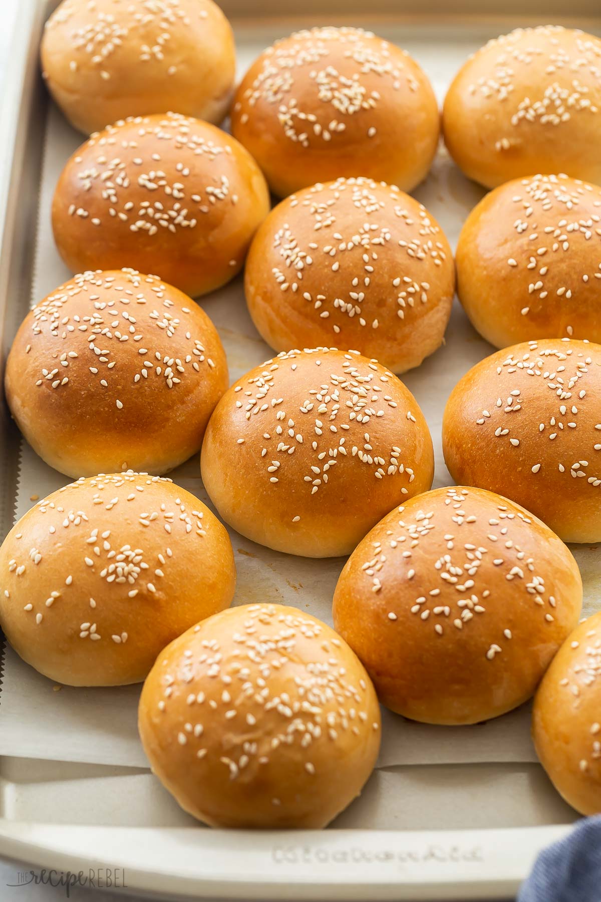 homemade hamburger buns on a baking sheet with sesame seeds