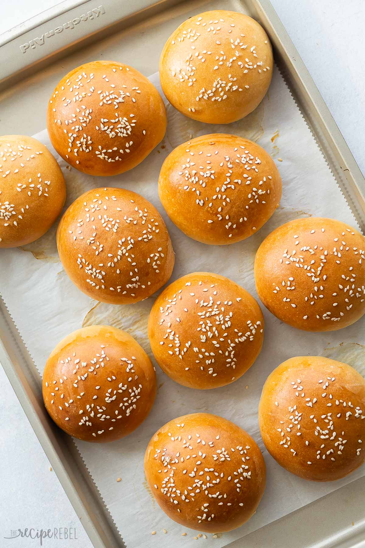 golden burger buns on a baking sheet with parchment paper