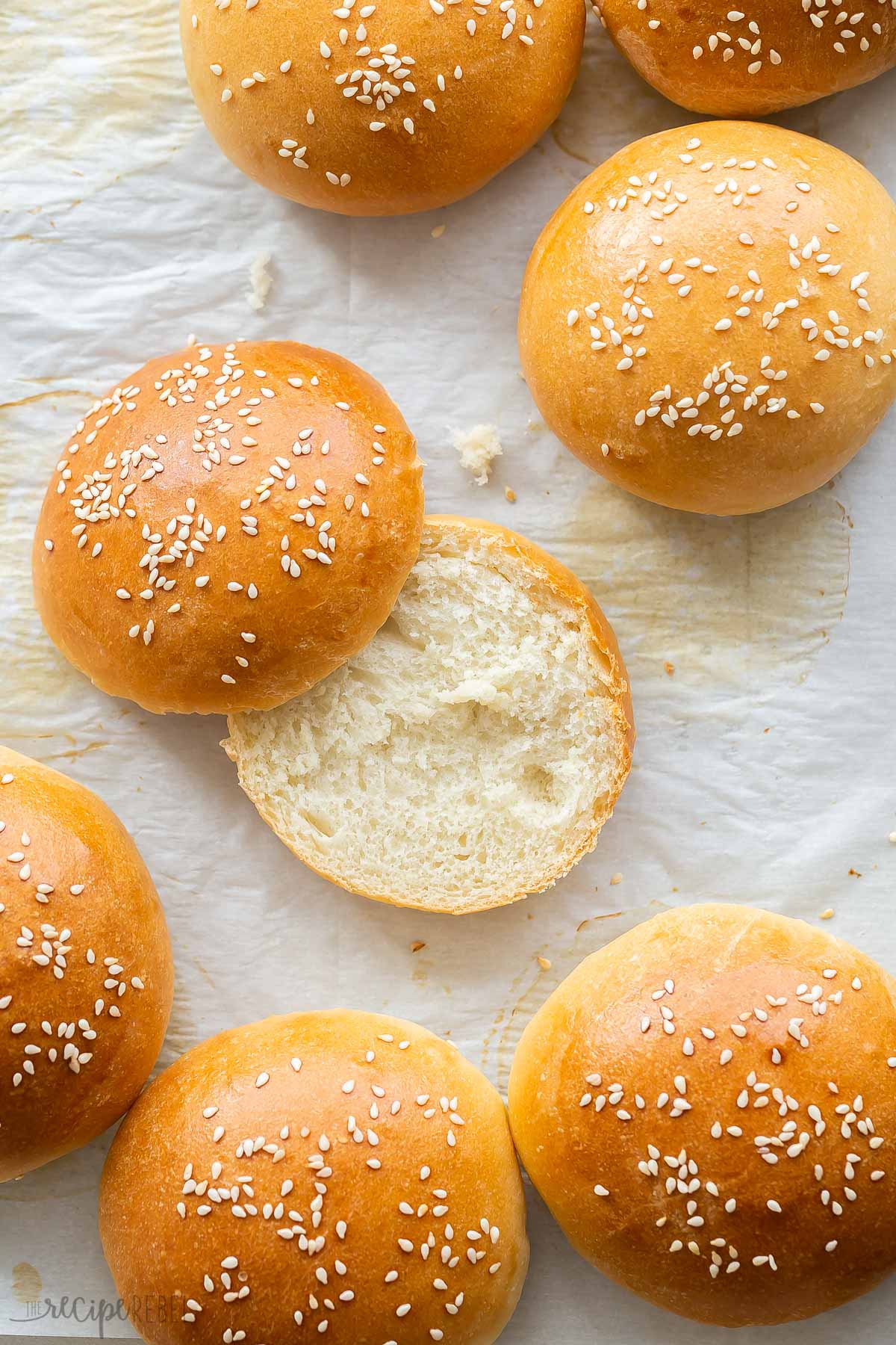 one hamburger bun sliced in half on parchment paper