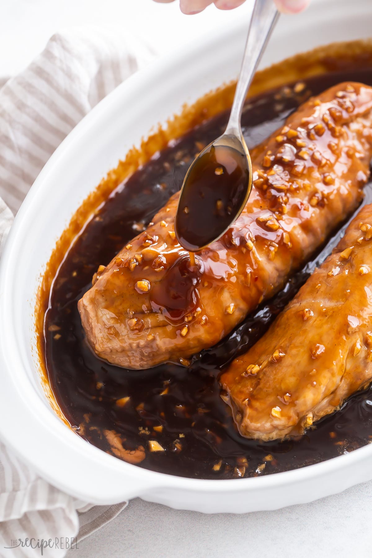 spoon drizzling honey garlic sauce over pork tenderloin