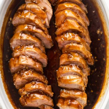 two pork tenderloins in honey garlic sauce in a white baking dish