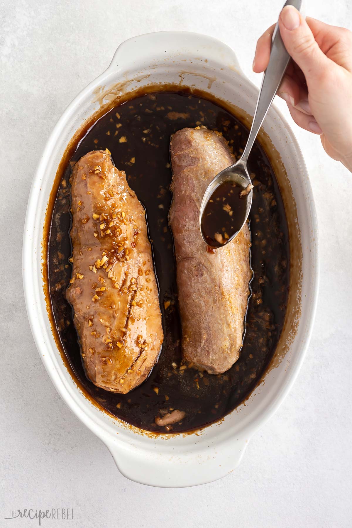 baked pork tenderloin with sauce being drizzled over