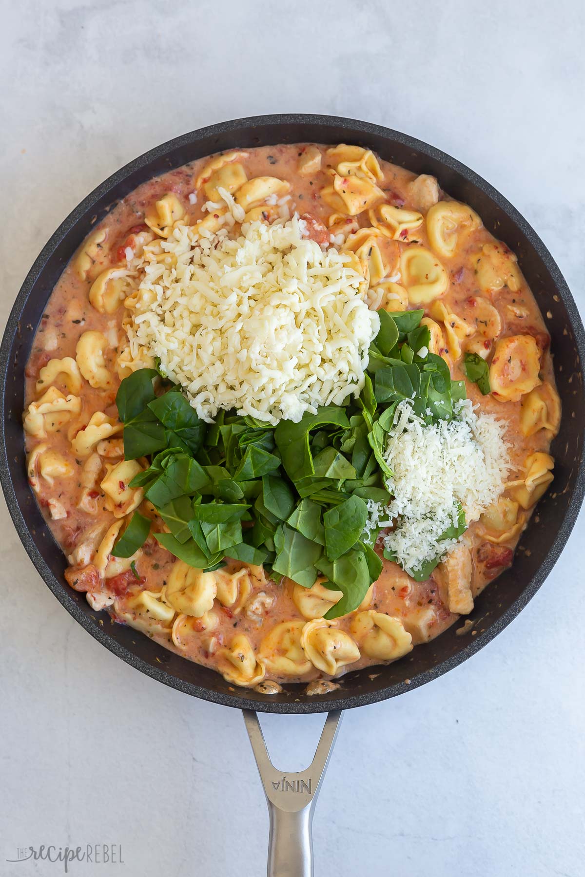 parmesan cheese and fresh spinach added to skillet with tortellini.