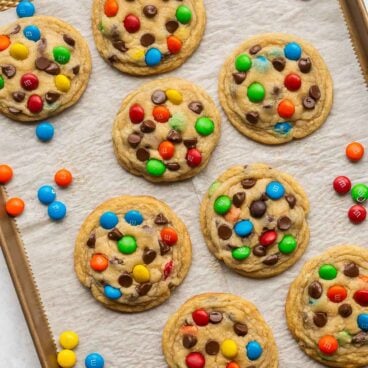 overhead image of eight M&M cookies on baking sheet.