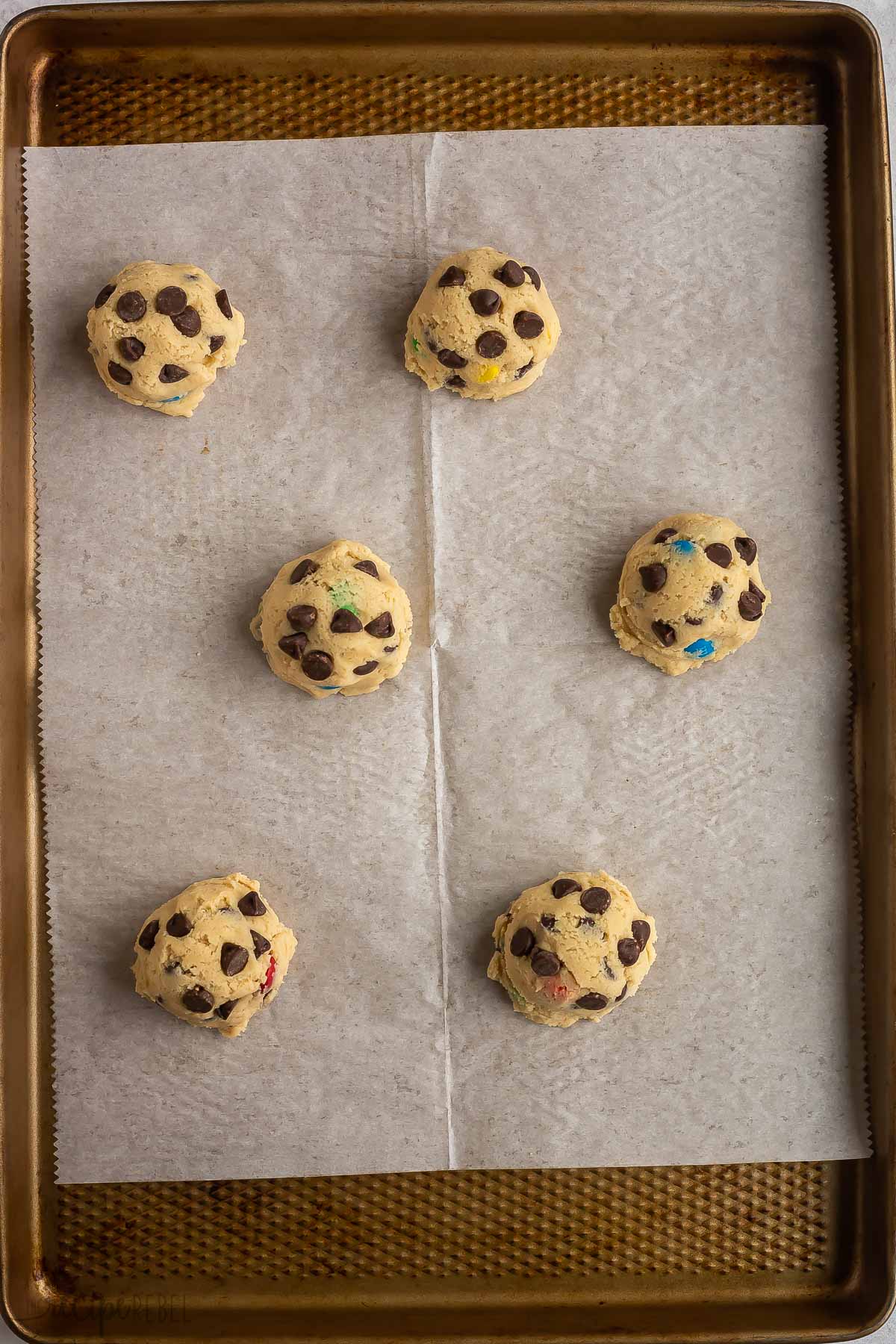 six cookie dough balls on baking sheet.