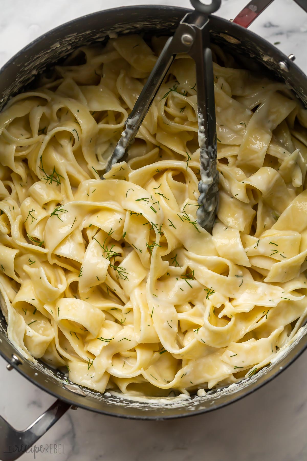 feta pasta with dill in large pot with tongs.