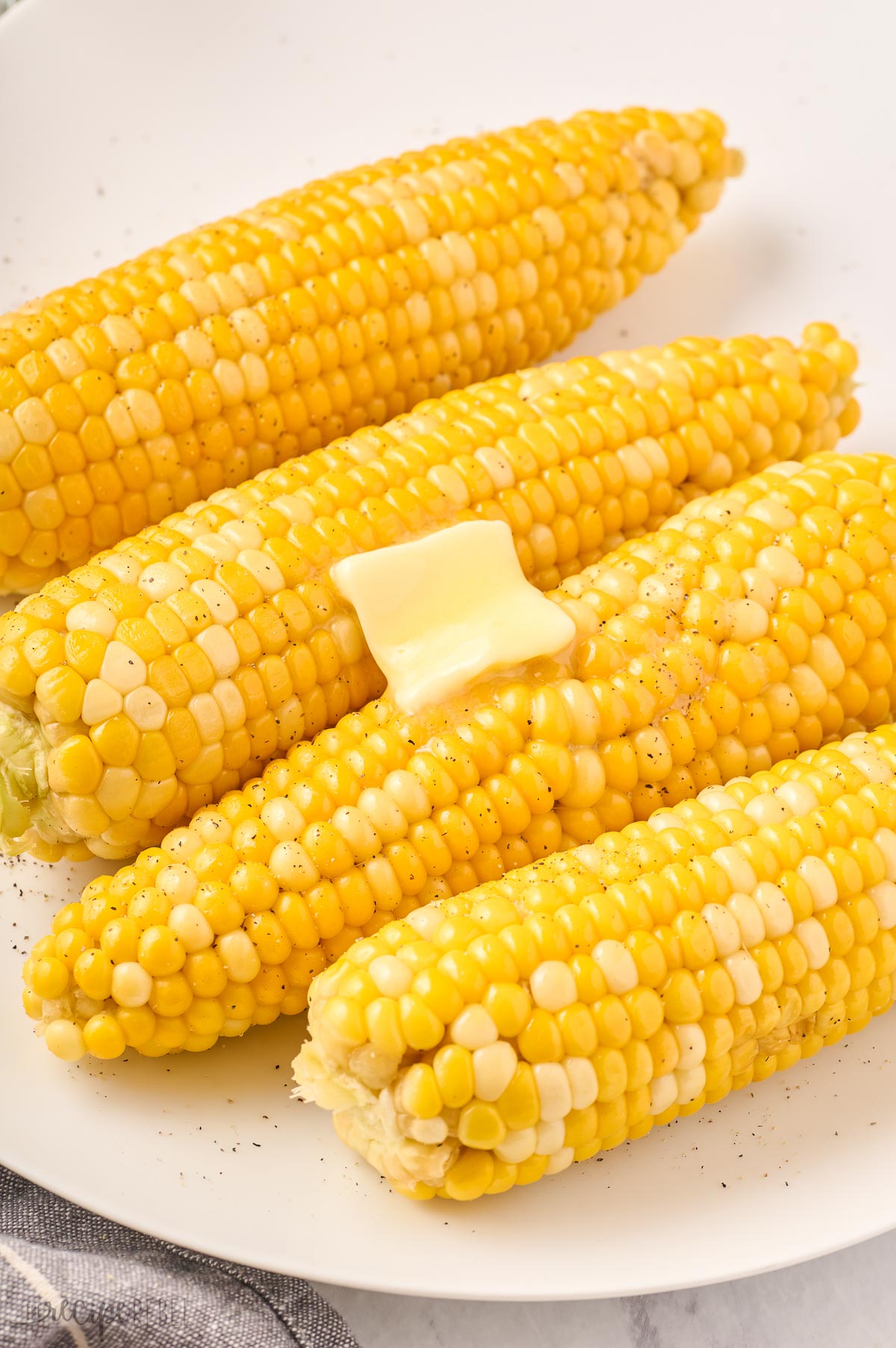 dab of butter on top of plate of corn on the cob.