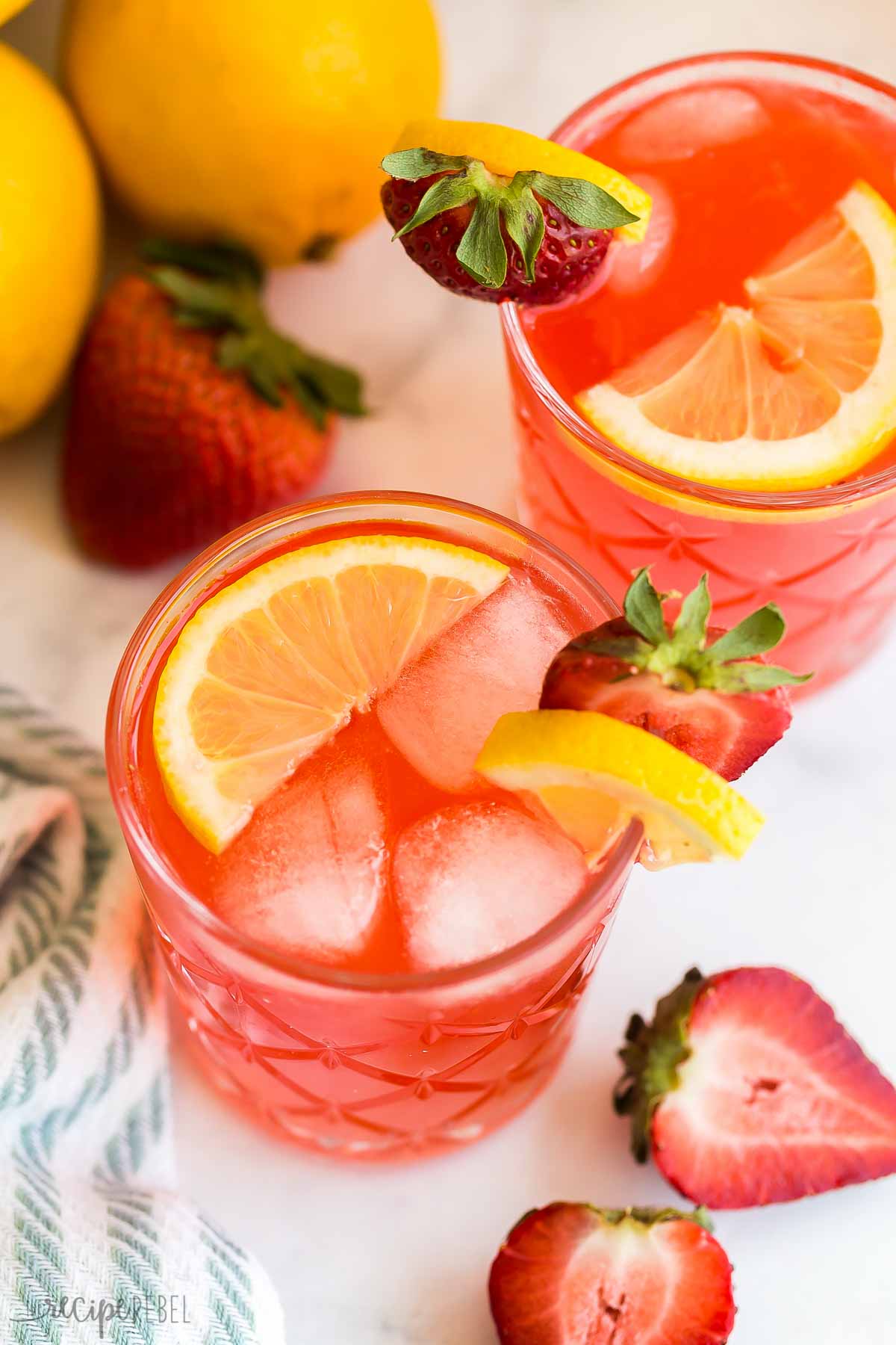 two glasses of strawberry lemonade with lemon slices and fresh strawberries.