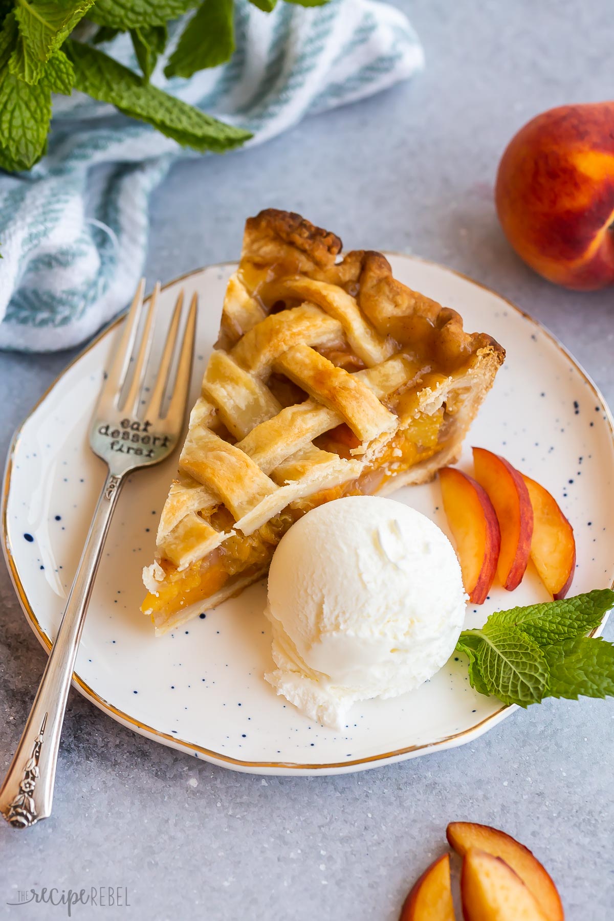 slice of peach pie on a white plate with ice cream.