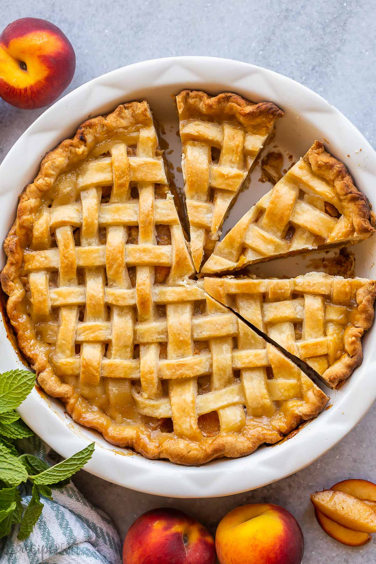 This Peach Pie is the best summer dessert! It's made with a buttery homemade pie crust filled with a sweet and saucy peach filling. Don't forget the ice cream! #peaches #dessert #recipes | peach recipe | peach dessert | pie recipe | summer dessert overhead image of whole peach pie with lattice crust.