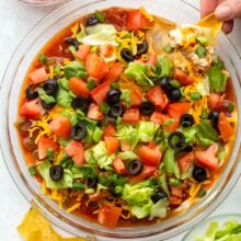 overhead image of a hand scooping taco dip.