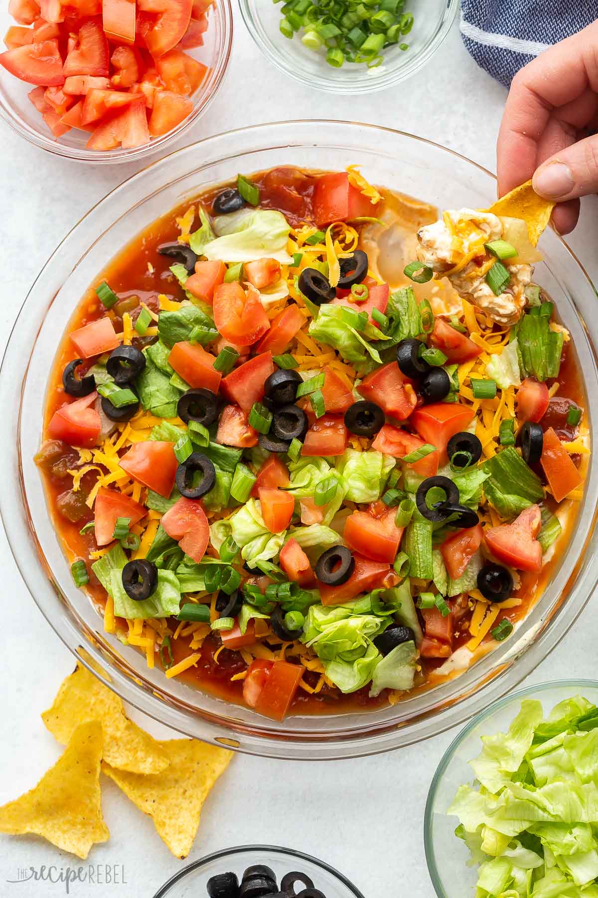 overhead image of a hand scooping taco dip.