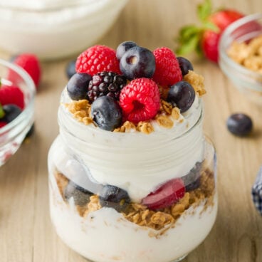 fresh raspberries blueberries and blackberries on top of yogurt parfait.