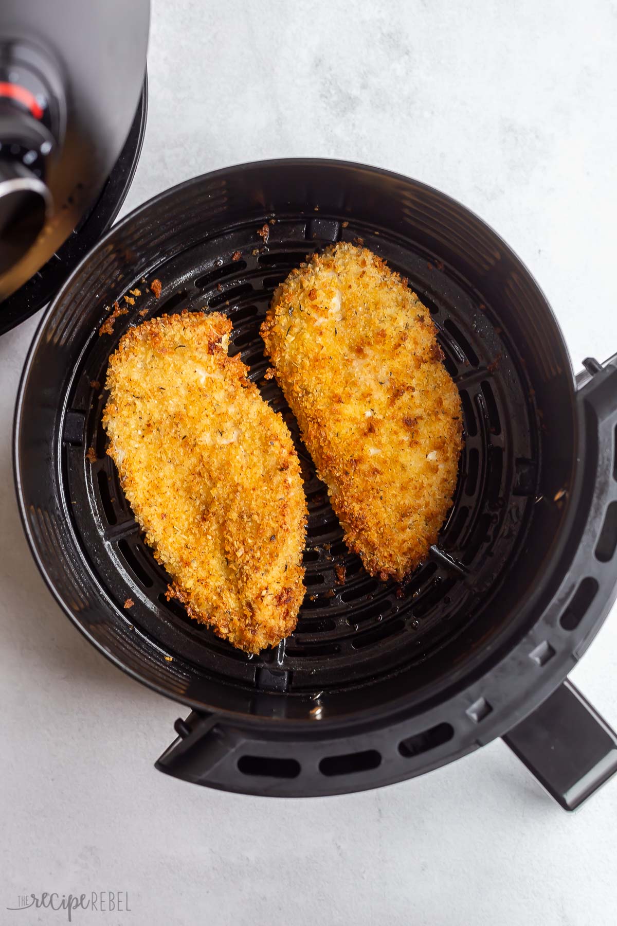 crispy coated air fryer chicken breast in air fryer basket.