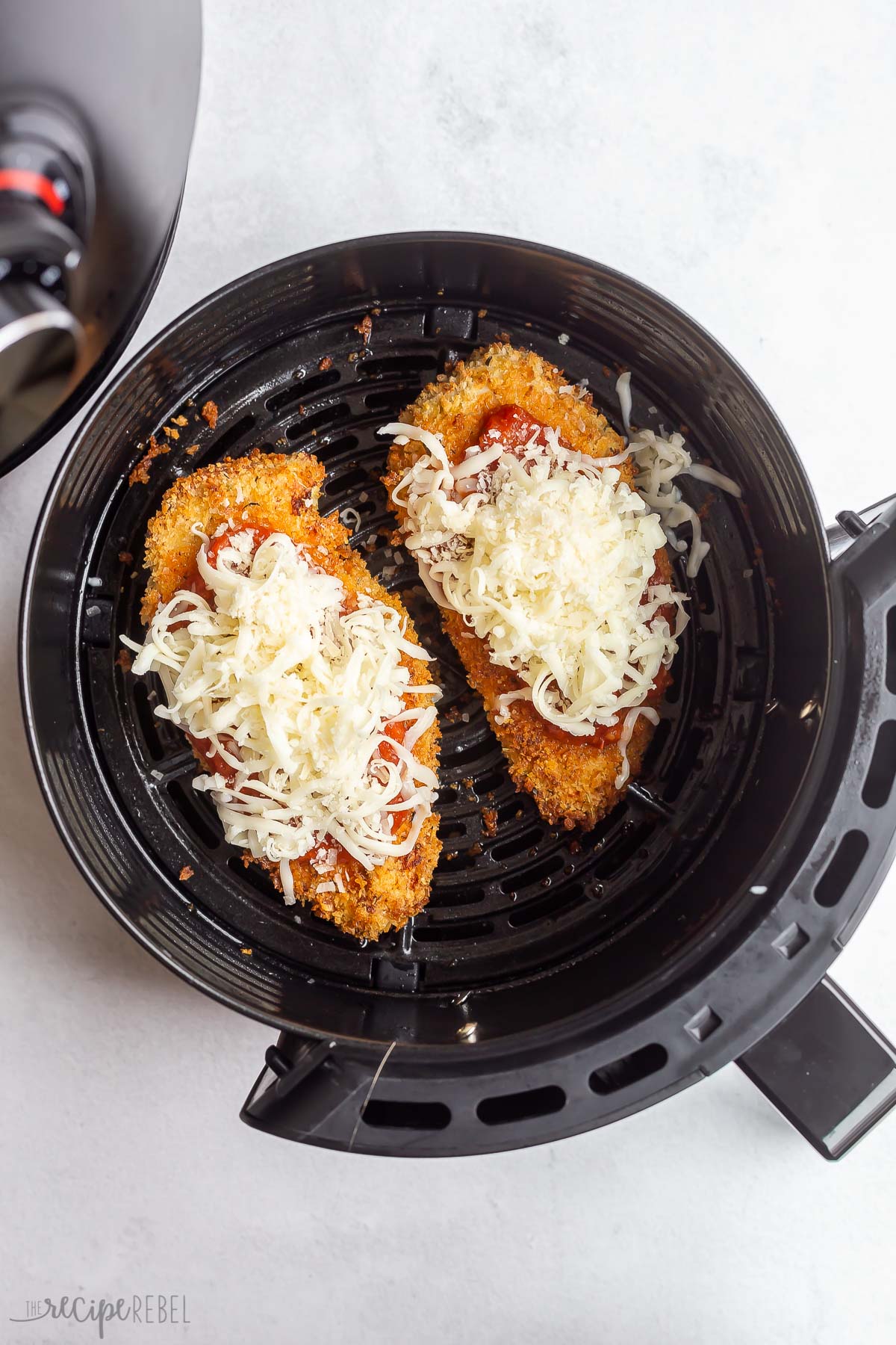 air fryer chicken with tomato sauce and cheese added on top.