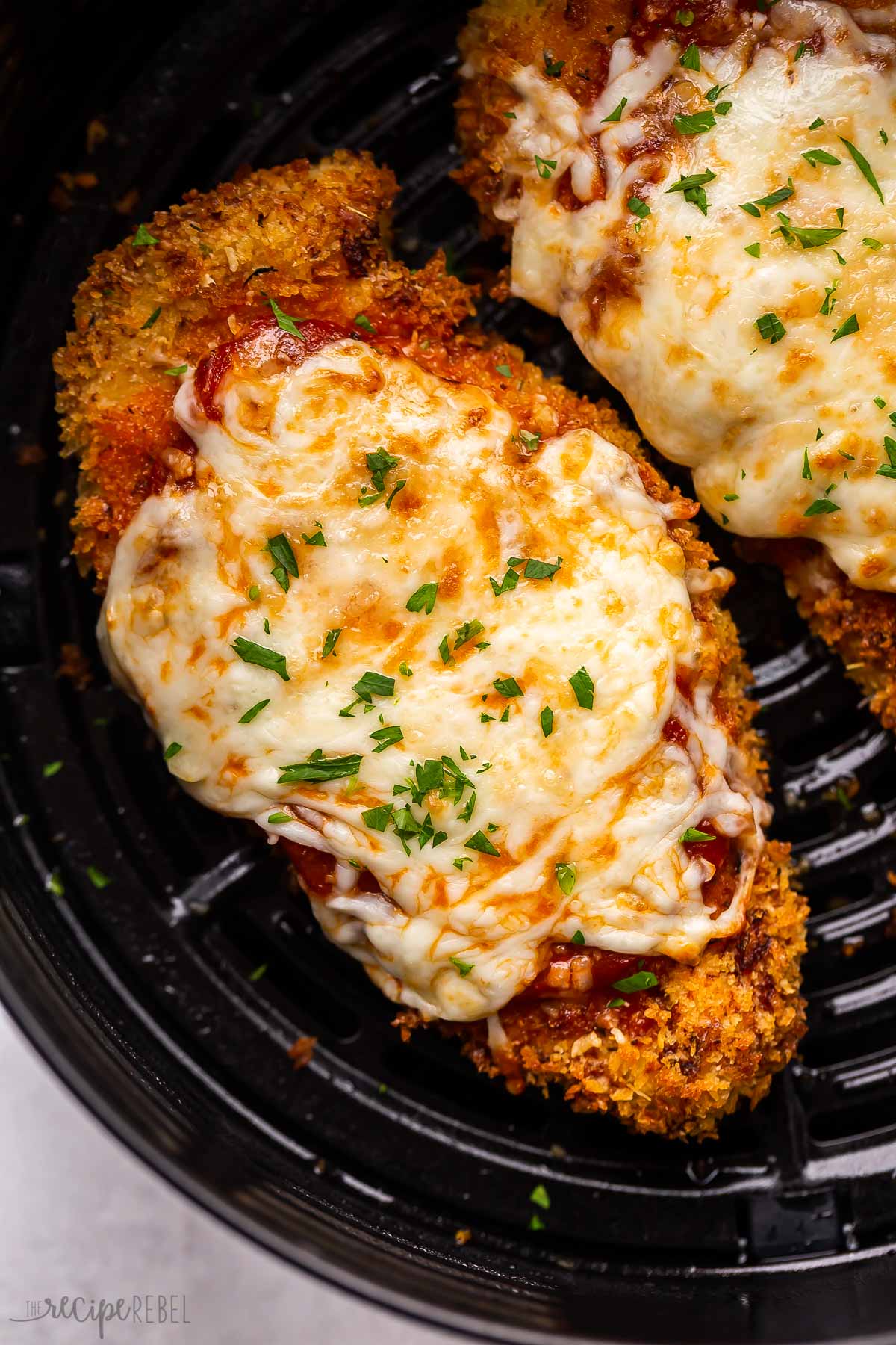 close up image of air fryer chicken parm in air fryer basket.