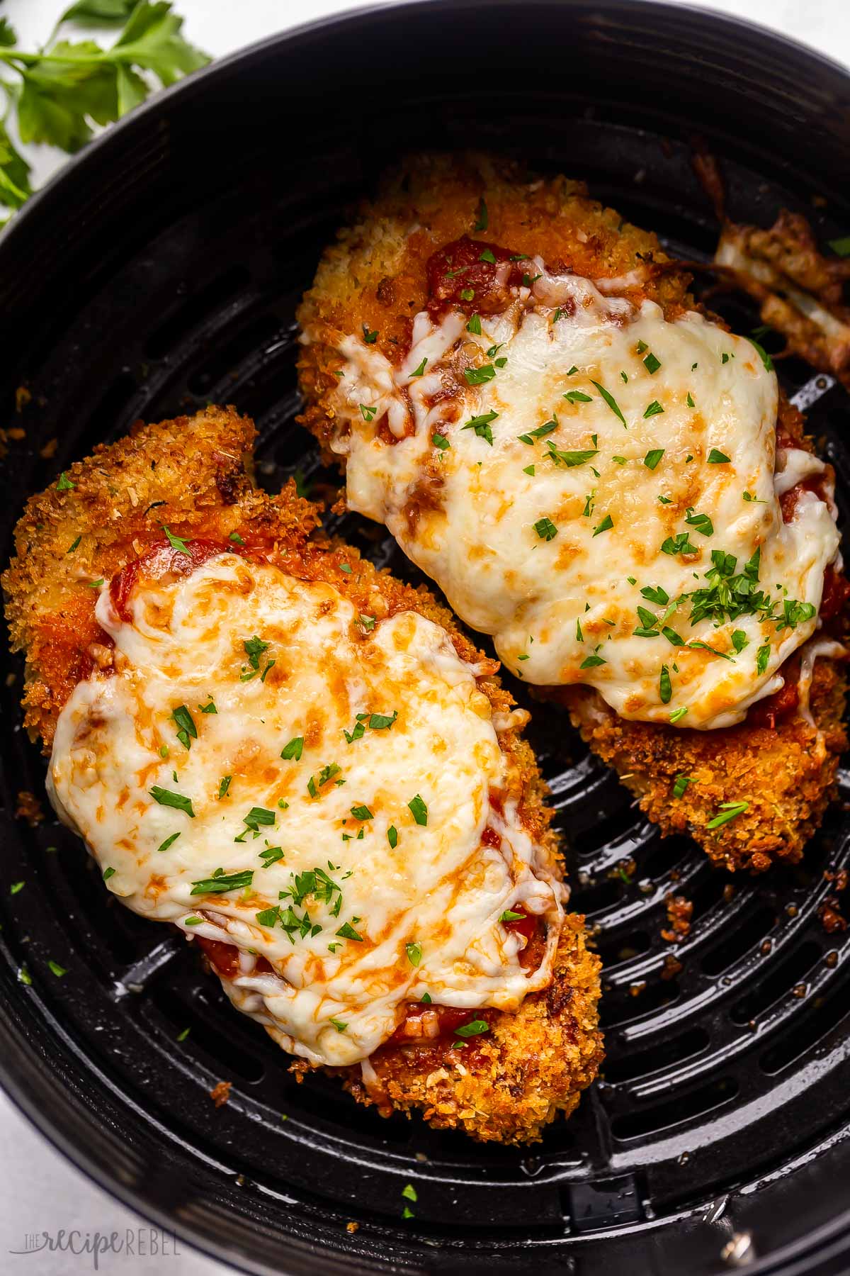 two air fryer chicken parmesan in air fryer basket.