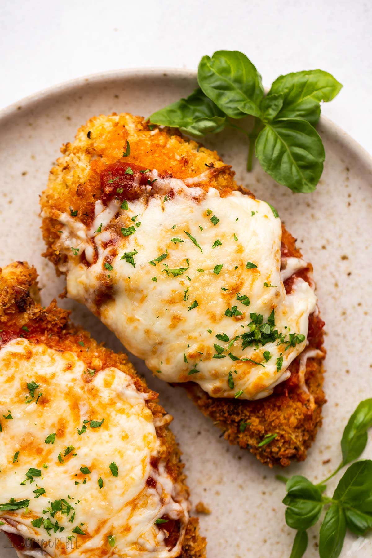 close up image of air fryer chicken parm on beige plate.