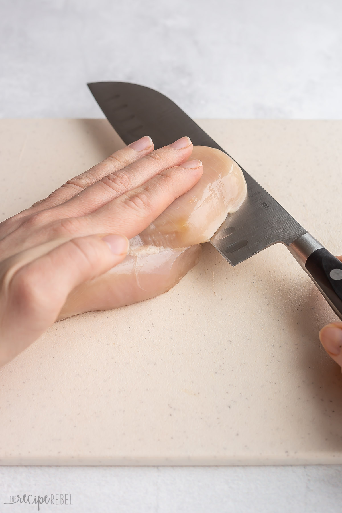 butterflying a chicken breast with a knife.