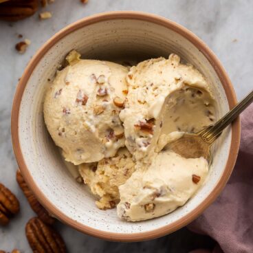 bowl of homemade butter pecan ice cream with spoon taking a scoop.