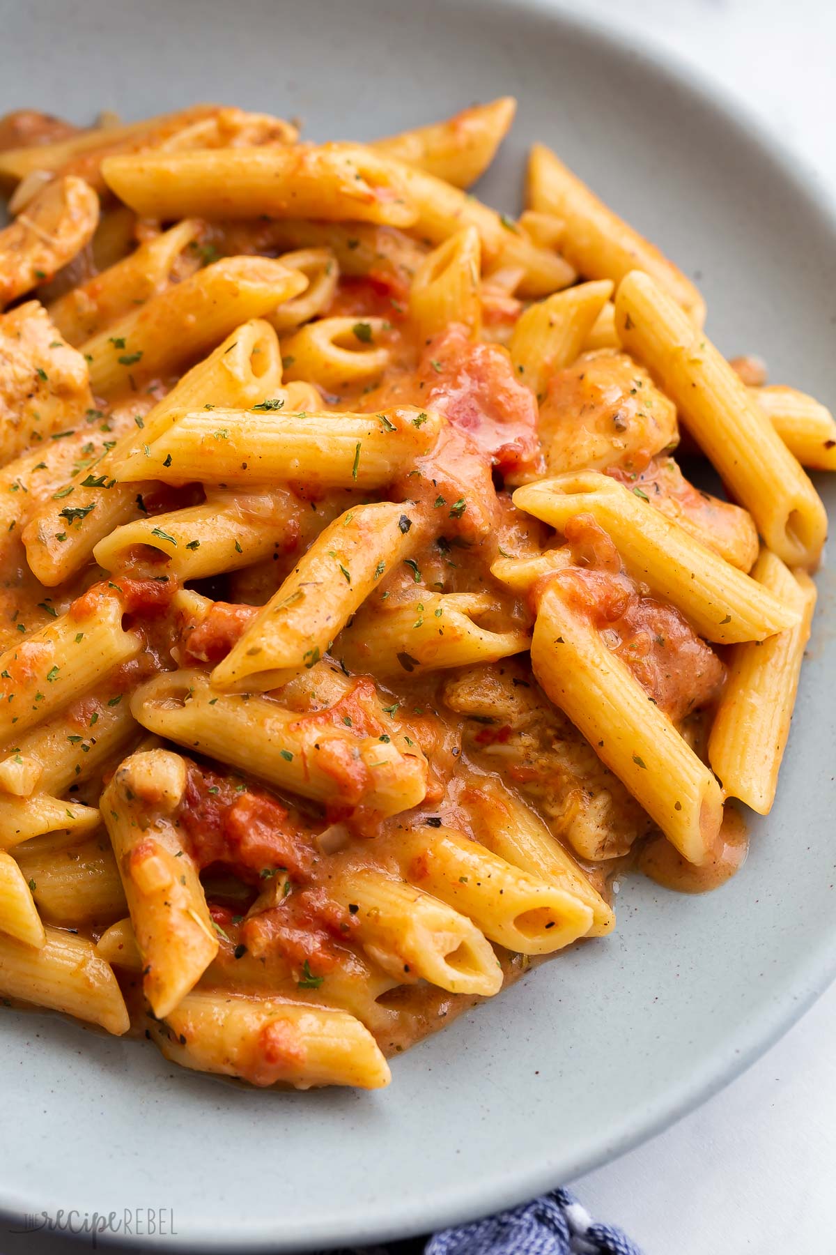 close up image of cajun chicken pasta on blue plate.