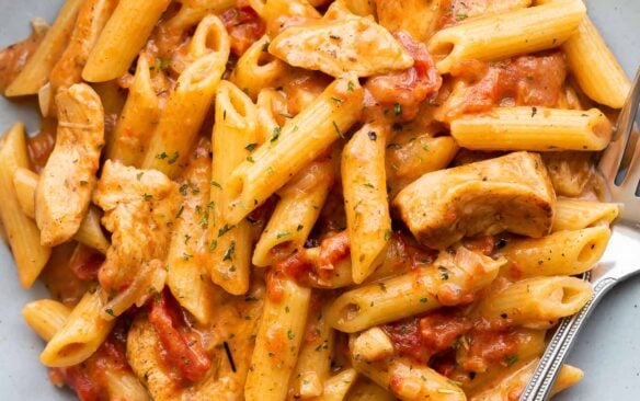 overhead image of cajun chicken pasta on blue plate with fork.