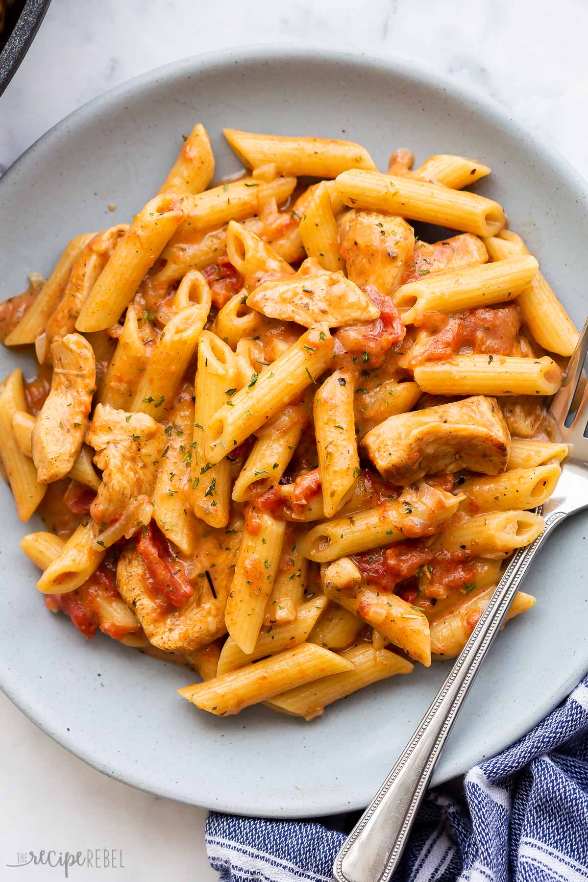 overhead image of cajun chicken pasta on blue plate with fork.