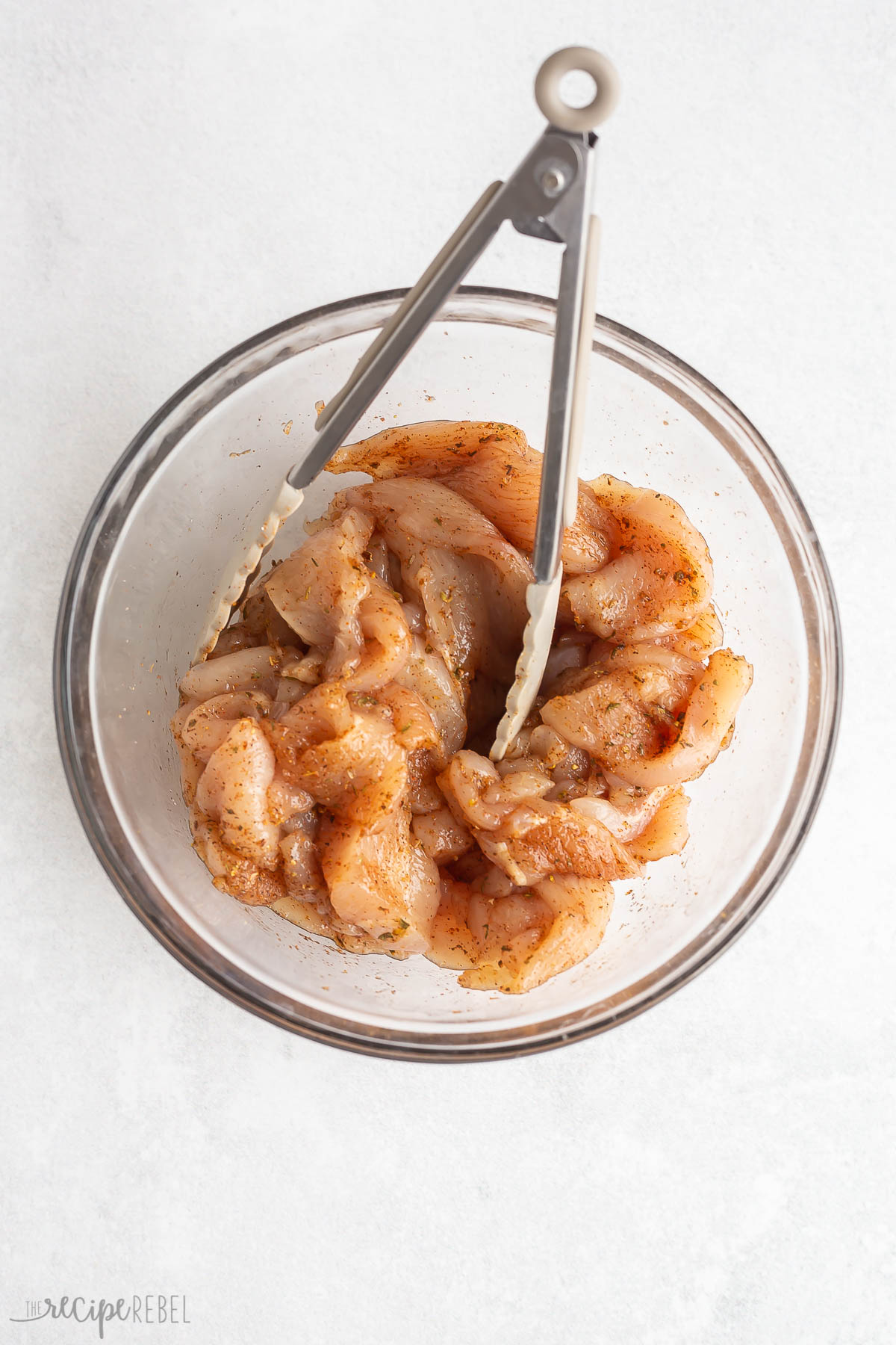 chopped chicken breasts being tossed with seasoning.