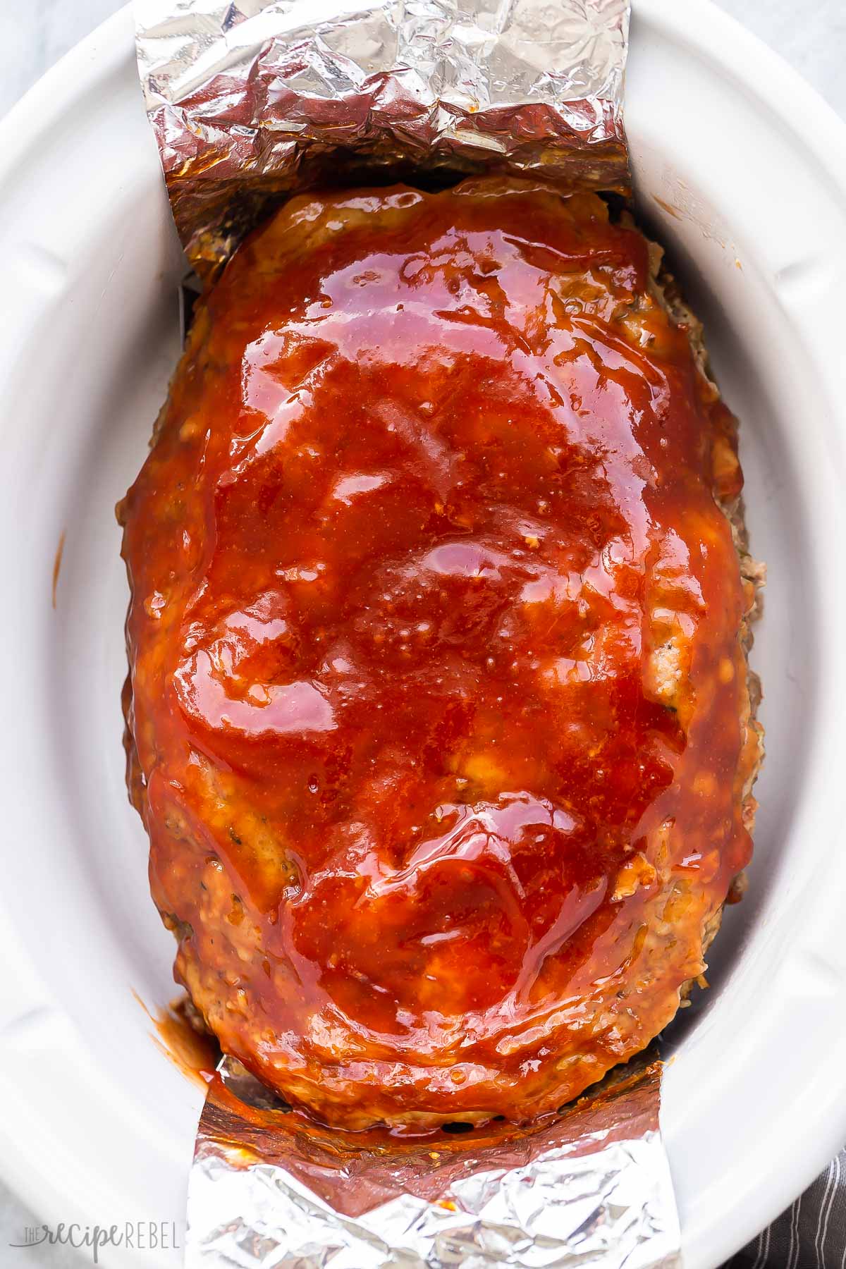 overhead image of crockpot meatloaf with glaze in slow cooker.