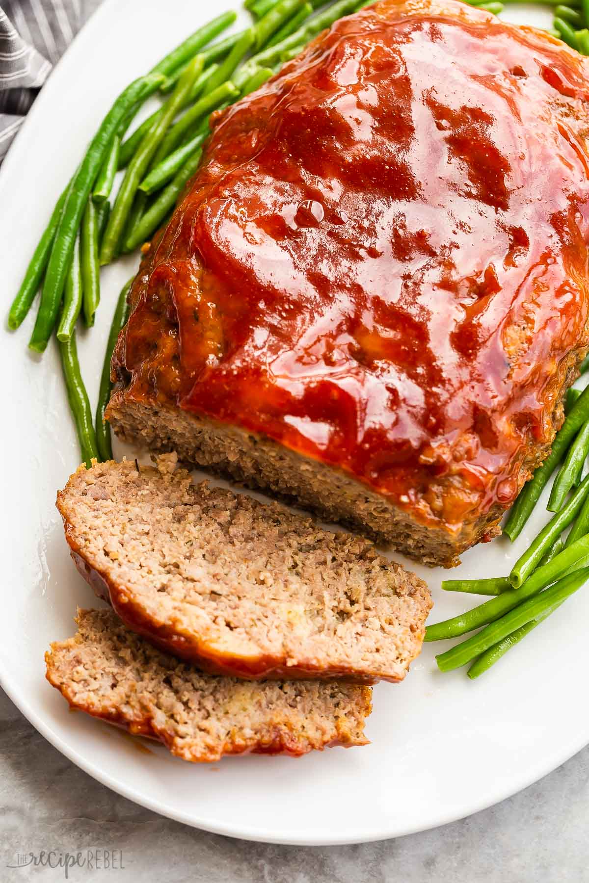 crockpot meatloaf on white platter with green beans.