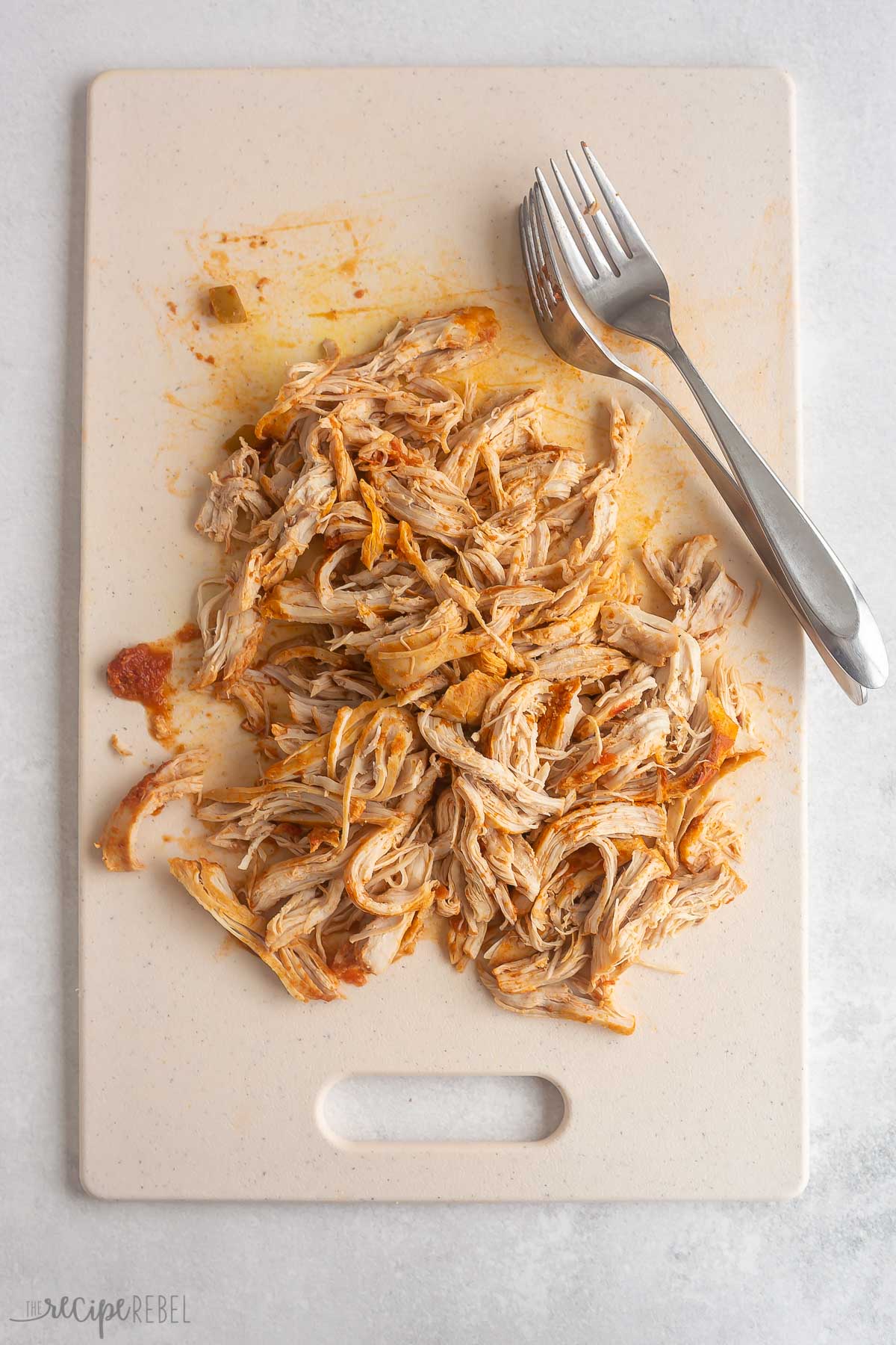 shredded chicken and two forks on a cutting board.
