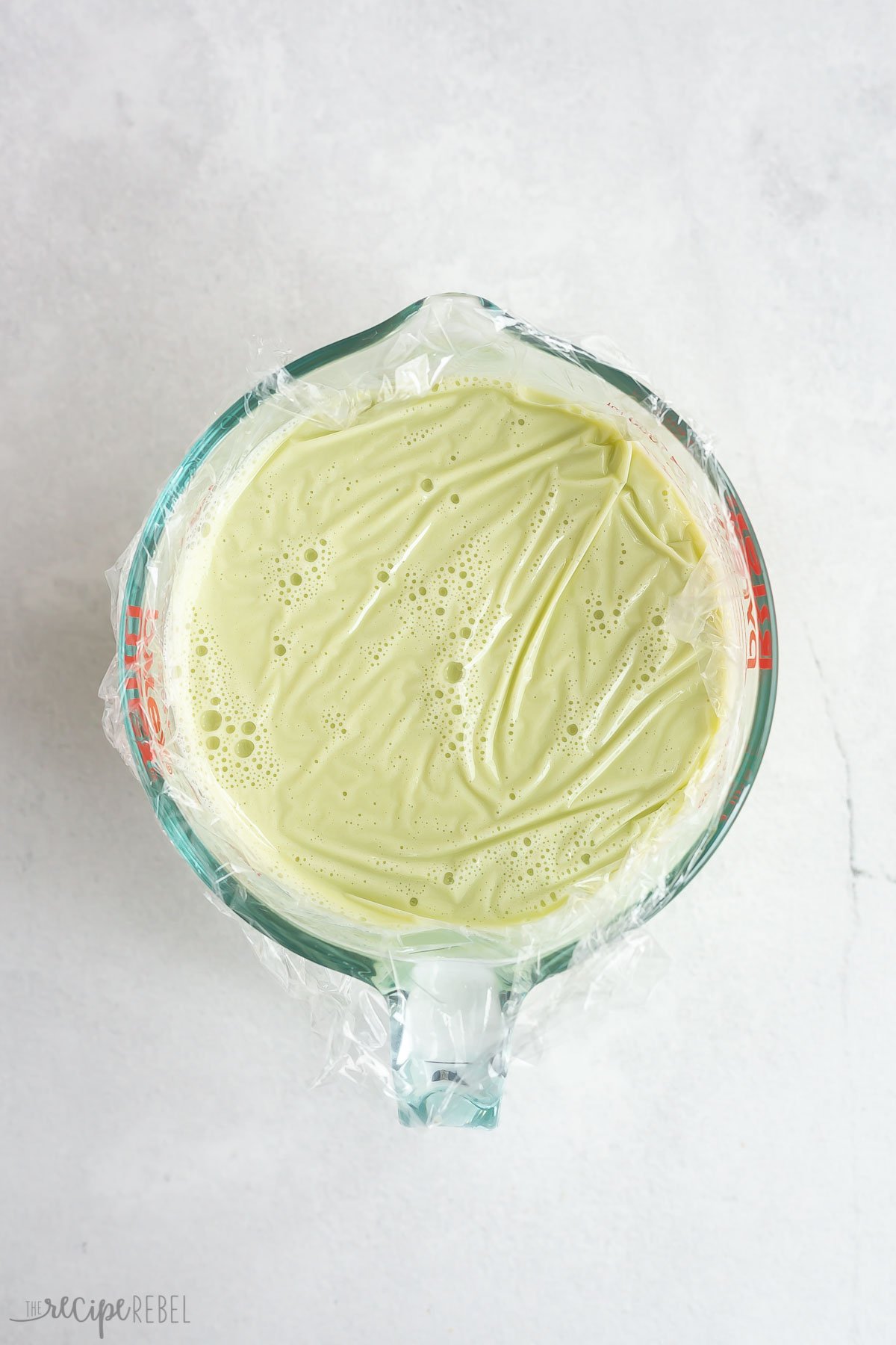 ice cream base chilling in glass measuring cup with plastic wrap.