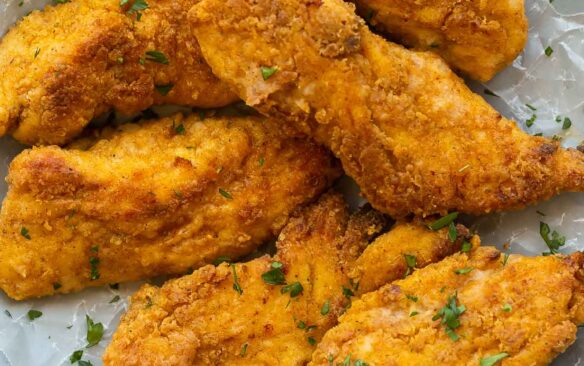 crispy oven fried chicken on a plate lined with parchment paper.