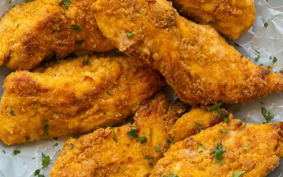 crispy oven fried chicken on a plate lined with parchment paper.