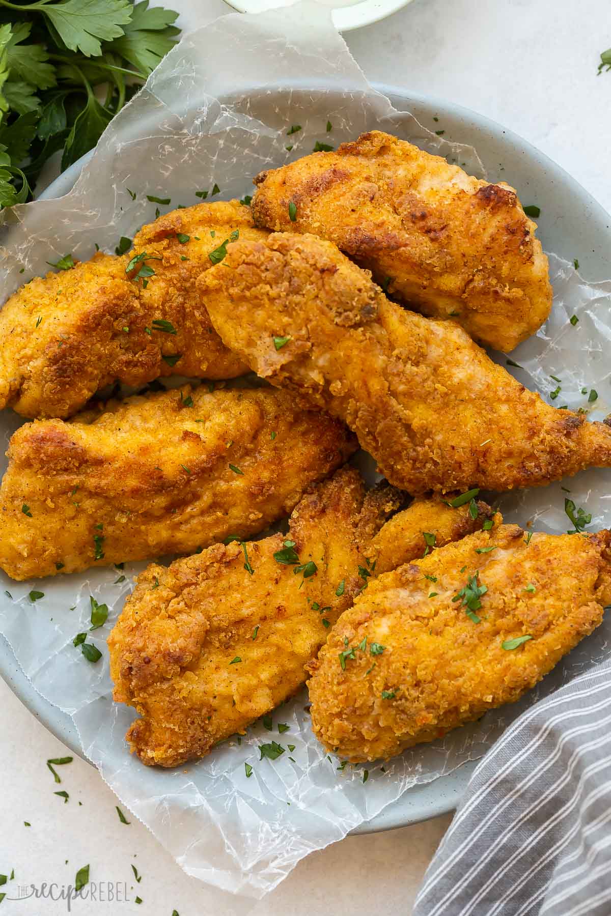 crispy oven fried chicken on a plate lined with parchment paper.