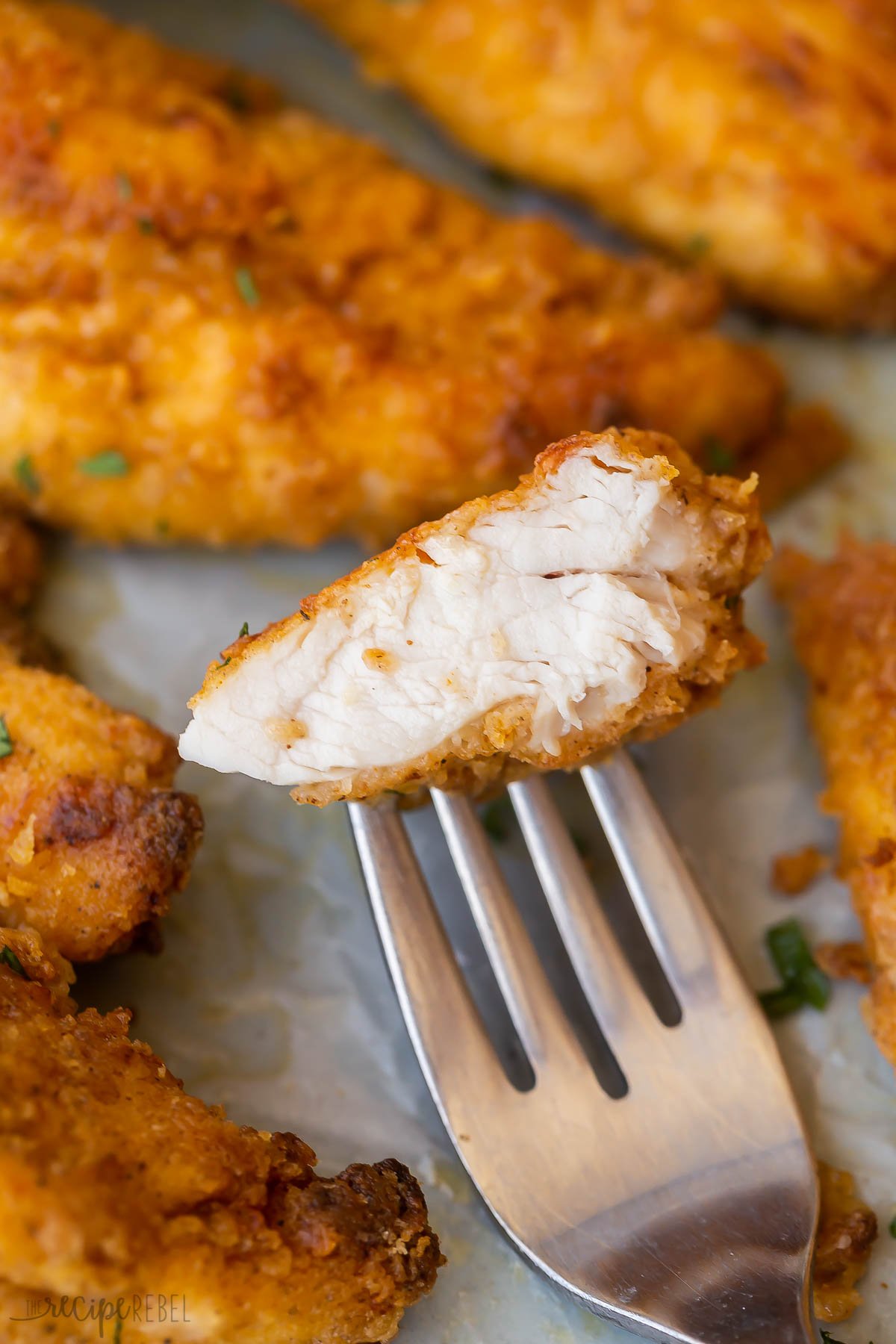 close up image of oven fried chicken piece on a fork.