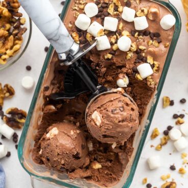 glass loaf pan with rocky road ice cream and two scoops of ice cream.