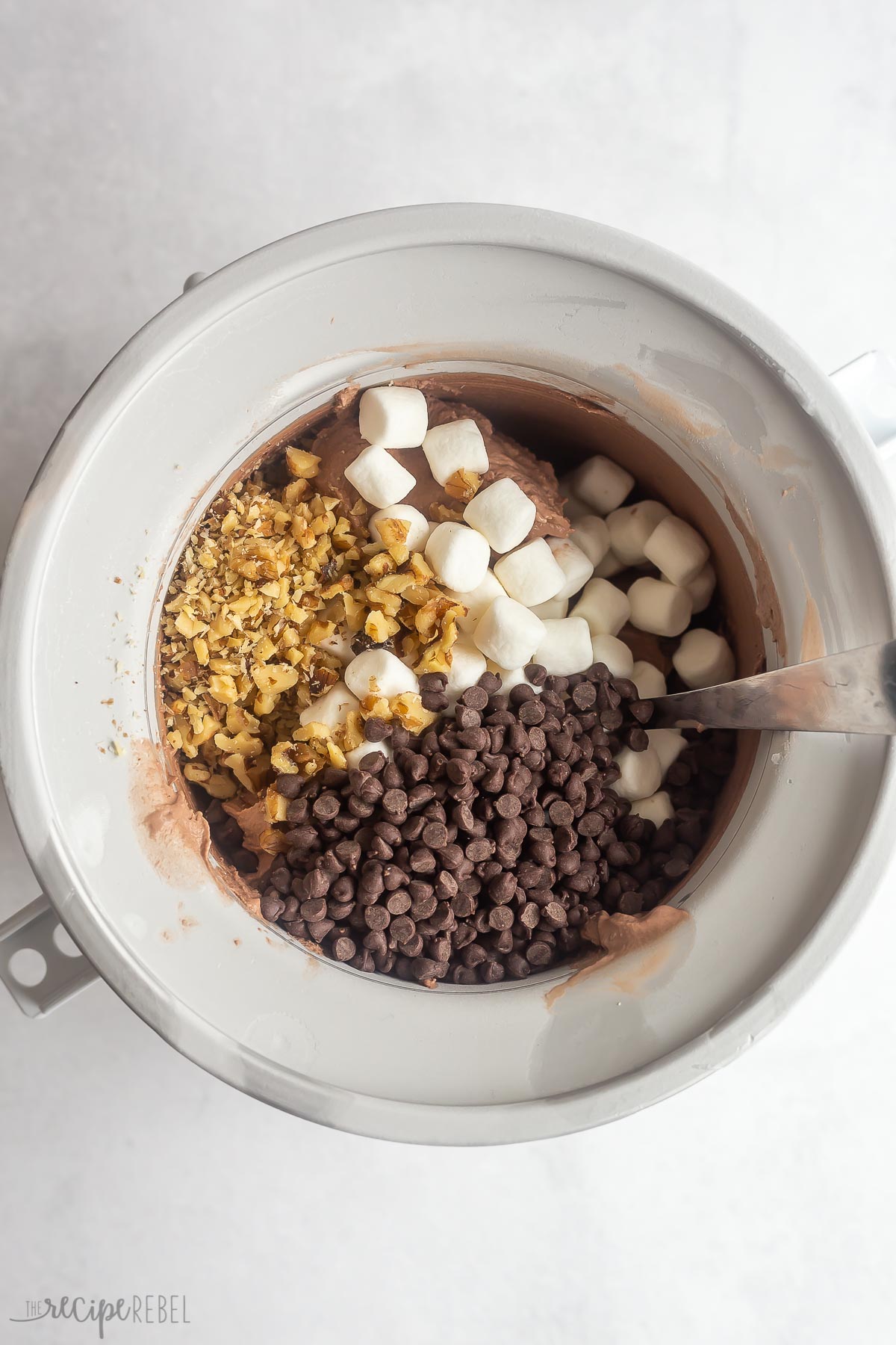 chocolate ice cream in ice cream maker with nuts marshmallows and chocolate chips.