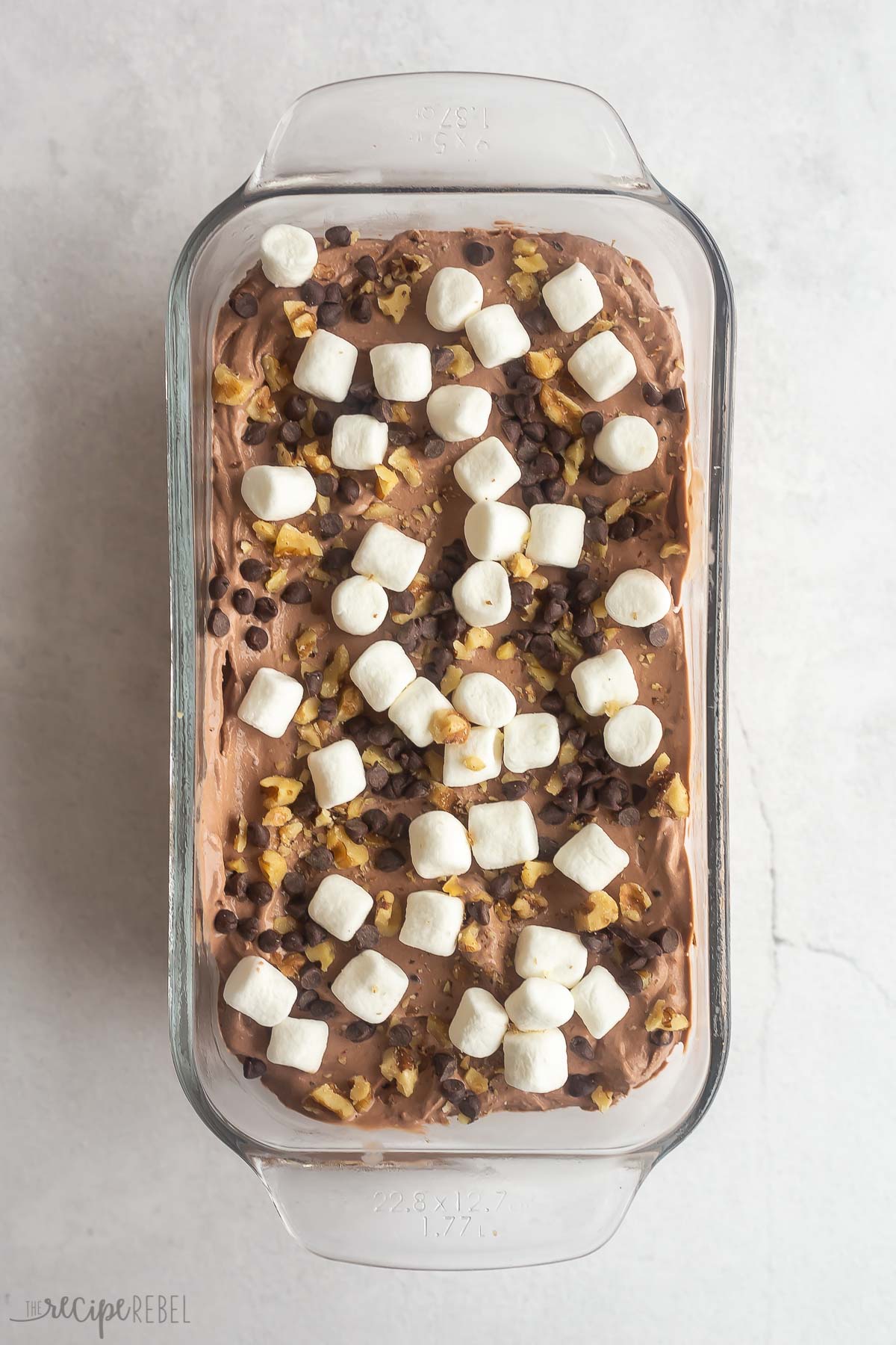 rocky road ice cream in loaf pan topped with marshmallows chocolate chips and nuts.