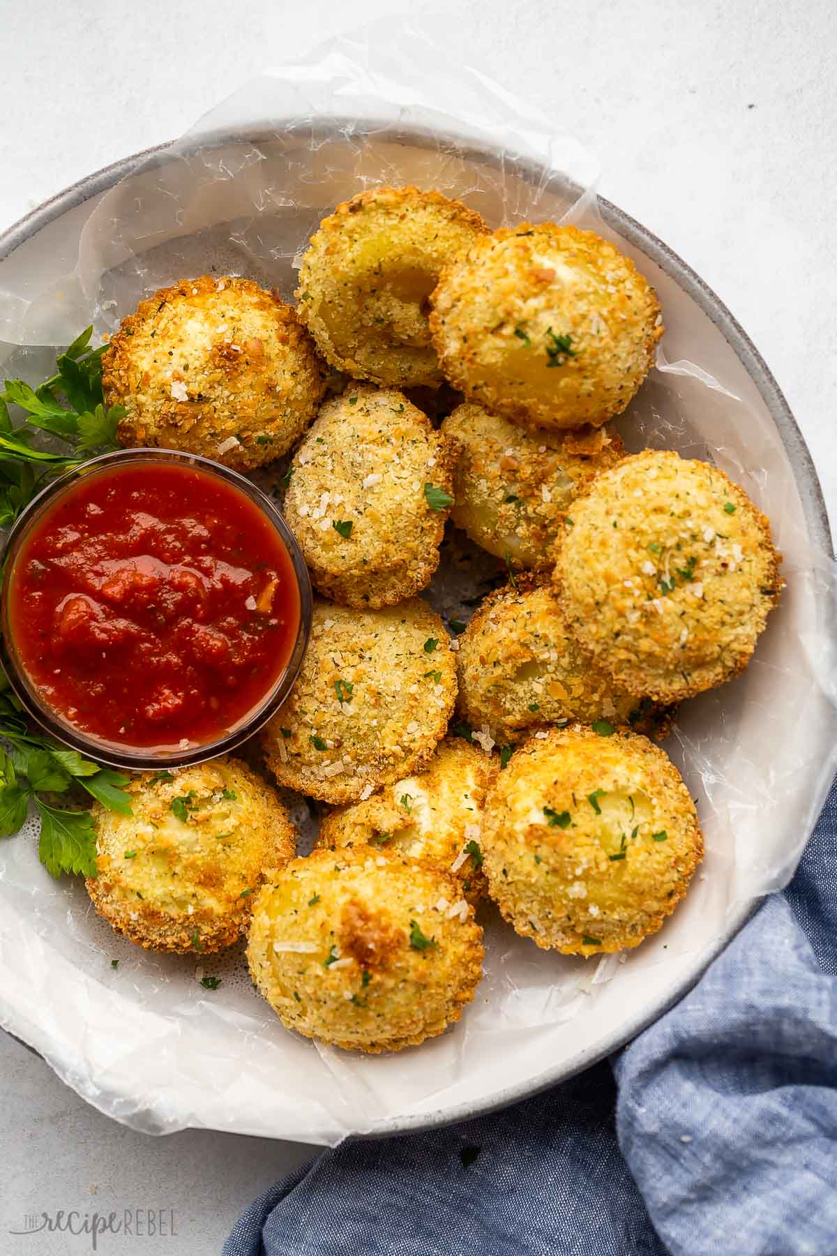 overhead image of air fryer ravioli on plate with tomato sauce.